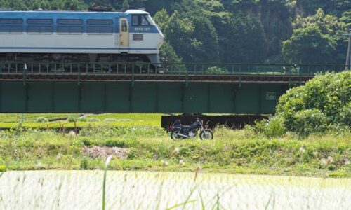 橋梁を通過する貨物列車とオートバイ