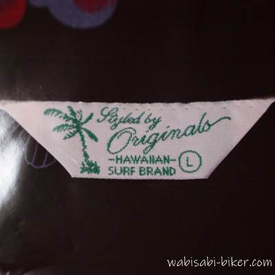 アロハシャツの襟元に縫い付けられたブランドタグ。“Styled by Originals / HAWAIIAN SURF BRAND / L”と記載あり。2021年に購入した金魚柄アロハと同じタグで、2024年の購入時にもこのタグを目印に選んだ記録用写真
