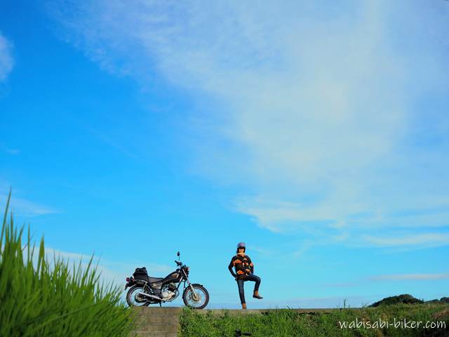 夏空と田んぼとポーズをとるバイク乗り