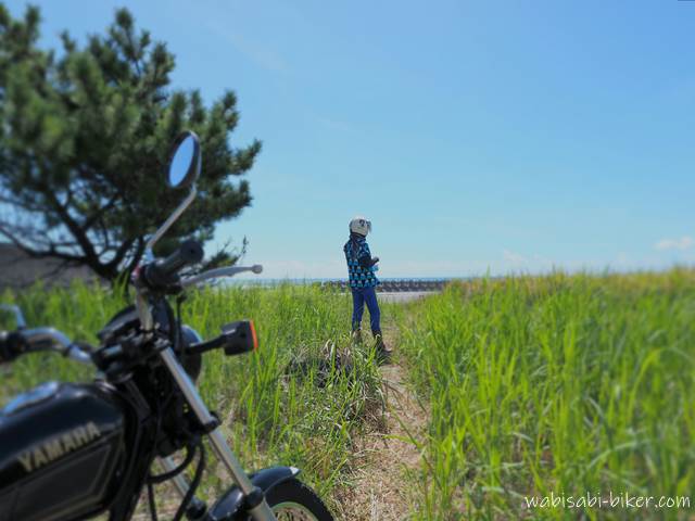 海へ続く小道とバイク乗り