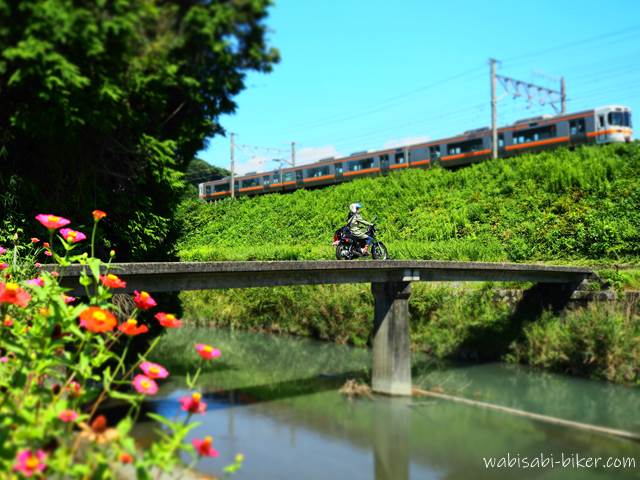 橋を渡るバイク乗りと通過する電車