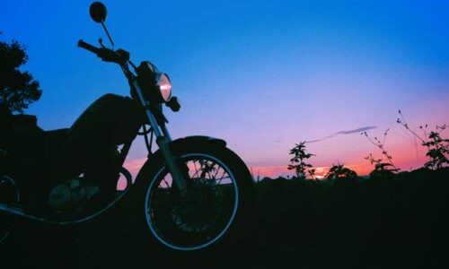 夕暮れ空を背景にシルエットで浮かび上がる黒いバイク(YAMAHA SR125)。フロントライトが灯り、空は青から紫、そして橙に移ろうグラデーションを描いている。