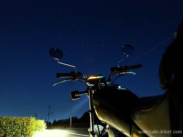 ブルーアワーの夜空の下、SR125のライトに照らされた茶畑と静かな直線道路。空にはオリオン座がかすかに浮かび、冬の夜にバイクを停めて見上げた風景が写っている。