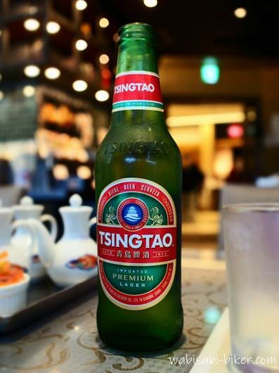 新横浜の梅蘭で提供された青島ビールのボトル。テーブルの上に置かれ、店内の照明が背景にぼけている。