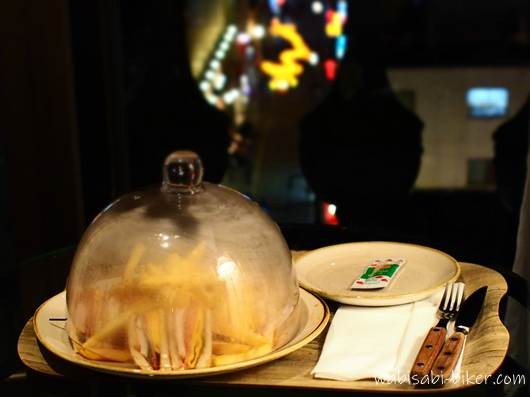 ローズホテル横浜の客室で提供されたルームサービスのクラブハウスサンド。クロッシュに覆われた状態で、背後の窓には中華街の春節燈花の龍の灯りがぼんやりと見える。