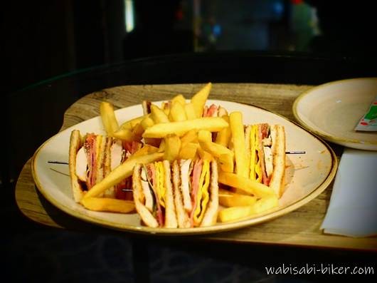 ローズホテル横浜の客室でクロッシュを外したルームサービスのクラブハウスサンド。三角にカットされたサンドとフライドポテトが皿に盛られている。