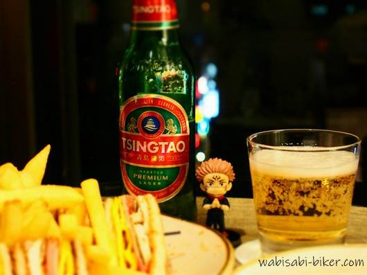 ローズホテル横浜の客室でクラブハウスサンドと青島ビール、宿儺のフィギュアを並べた一人時間の様子。