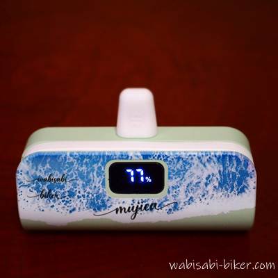 名前入りモバイルバッテリー。wabisabi-biker mujicaの装飾文字と背景は波のデザイン。