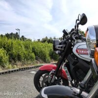 黒いバイクSR125と白と赤のXSR900がお茶の木が生える駐車場に並んで停車した写真。