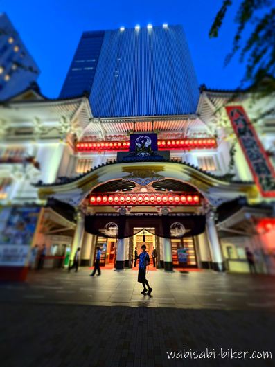 夜の歌舞伎座の正面入口前で撮影した記念写真。赤い提灯が灯り、背後には高層ビルが見えている