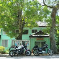 木陰に停めた2台のバイクと旧伊久美銀行として明治期に建てられた二俣公会堂。白いXSR900と黒いSR125が並んでいる。