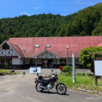 193 VALLEY BREWING前に停めたヤマハSR125。赤い屋根と緑の山を背景にした写真。