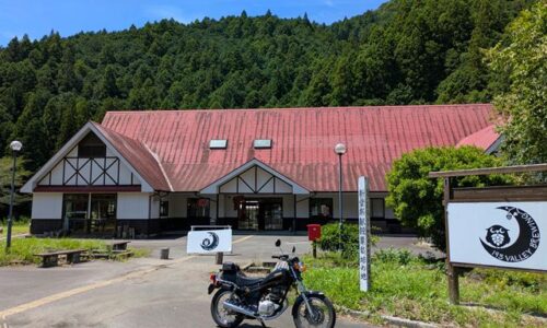 193 VALLEY BREWING前に停めたヤマハSR125。赤い屋根と緑の山を背景にした写真。