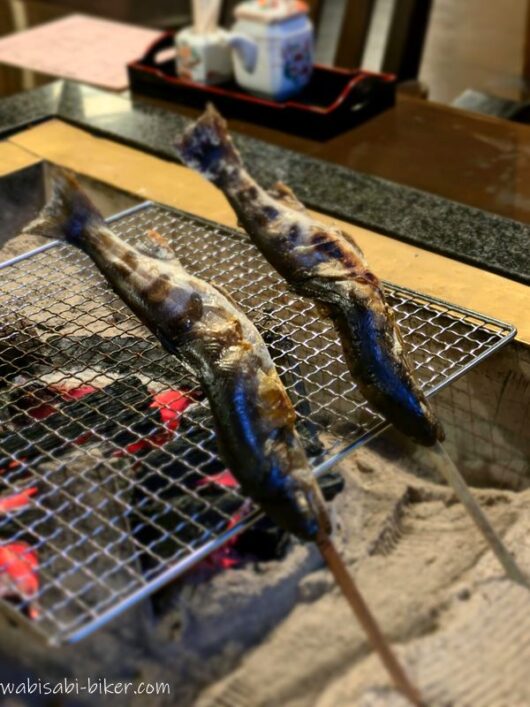 囲炉裏の炭火で焼かれる2尾のアマゴの塩焼き