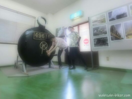 千頭駅のSL資料館で、SLの前面部分の展示と一緒に記念撮影する夫婦。